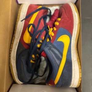 Nike sb dunk low barcelona color way - Nike Dunk Low sneakers med färgstark design i rött, blått och gult. Ovandel i mjuk mocka, klassisk gul Swoosh och matchande gula skosnören. Låg modell med platt sula och rund tå, perfekt för dig som gillar streetwear och unika färgkombinationer. Du får blåa och röda extra snören till skorna priset är ej hugget i sten, har du några frågor så är det bara att skicka mvh Benjamin