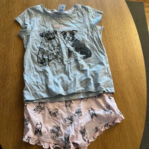 Rosa shorts med hundmotiv från KappAhl - Supersöta rosa shorts från KappAhl med tryck av olika hundar och volangkant nedtill. Perfekta för sommaren och riktigt mjuka i bomull. Matchar lätt med en enkel t-shirt för en chill look.