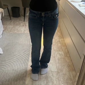  låg midjade bootcut Gina  - Säljer ett par blå jeans med bootcut-modell och låg midja. Jeansen har klassiska fickor fram och bak, dubbla knappar i midjan. Är 155 cm lång, storlek 158. Nypris 300 kr mitt pris 180