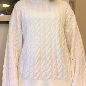 Vit kabelstickad polotröja - Mysig vit kabelstickad polotröja med lång ärm och ribbade muddar. Tröjan har en klassisk polokrage och är perfekt för kyliga dagar. Oversized passform för en avslappnad look. (endast testad)
