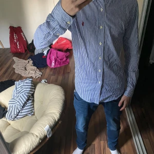 Randig skjorta från Ralph Lauren - Säljer en klassisk blåvit randig skjorta från Ralph Lauren med lång ärm och knappar hela vägen. Skjortan är i utmärkt skick och knappt använd. 