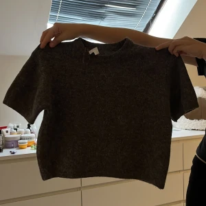 Mörkbrun stickad kortärmad tröja - Mysig mörkbrun stickad tröja med korta ärmar och rund hals. 