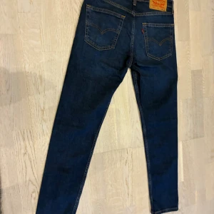Levi's 515 mörkblå jeans W28 L30 - Mörkblå Levi's 515 jeans med klassisk femficksdesign och snygga kontrastsömmar. Jeansen har rak passform och är tillverkade i slitstarkt denimtyg. Perfekta för dig som gillar en tidlös look med en modern touch.
