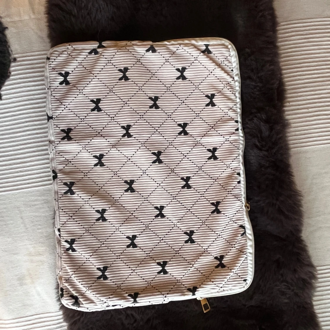 Beige datorväska med svarta rosetter.