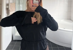 Svart blus med öppen rygg  - Säljer en svart blus med lång ärm och snygg öppen rygg. Blusen har en rund hals och ett elastiskt parti i midjan som ger en schysst passform. 