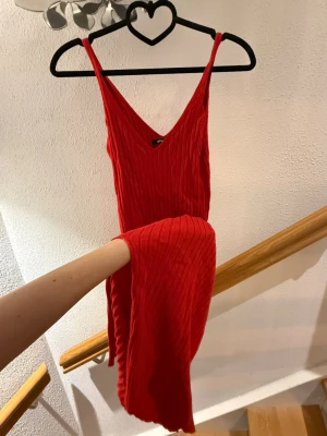 Röd ribbad långklänning Gina Tricot - Säljer en snygg röd långklänning från Gina Tricot i storlek XS. Klänningen är ribbad, har v-ringad hals och smala axelband. Materialet är stickat och ger en skön känsla. Perfekt för dig som gillar färgstarka och trendiga plagg.