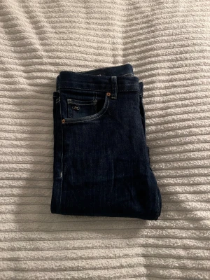 Mörkblå skinny jeans från J.Lindeberg - Snygga mörkblå skinny jeans från J.Lindeberg med klassisk femficksdesign och kontrastsömmar. Jeansen har en läderpatch med logga bak och raka bakfickor med unik söm. Perfekt passform och stilren look för dig som gillar smala ben.