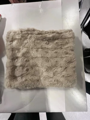 Beige päls-datorfodral - Säljer ett fluffigt beige datorfodral med swirl-liknande mönster i pälsen. Datorfodralet har en mjuk och lyxig känsla, perfekt för att ge din outfit en extra touch. Passar dig som gillar att sticka ut med coola detaljer och vill ha något riktigt mysigt.