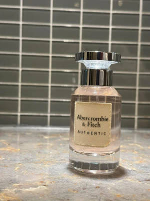 Abercrombie & Fitch Authentic parfym - Stilren parfym från Abercrombie & Fitch med modern design. Perfekt för dig som vill ha en fräsch och trendig doft i din samling. Flaskan har en enkel och snygg look som passar in i alla miljöer. Kommer med sin förpackning.