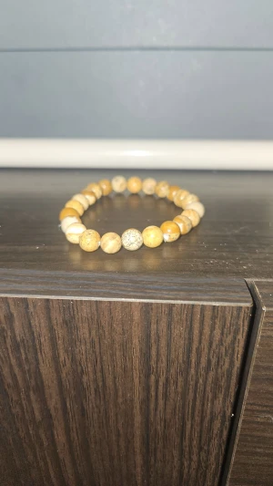 Ingen väst på bilderna - Bilderna visar ett armband med runda pärlor i beige och bruna toner, säljer nu detta armband som jag köpte utomlands vet tyvär inte var de är för märke eftersom det inte står något på. Mer bilder går givetvis att lösa