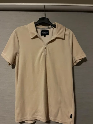 Beige kortärmad polotopp från Bondelid - Säljer en beige polotopp från Bondelid i storlek S. Toppen har korta ärmar, krage och en halv dragkedja framtill. Materialet frotté och har en lätt glansig yta som ger en skön känsla. Perfekt för dig som gillar stilrena och enkla plagg. Hör av dig vid intresse🤩