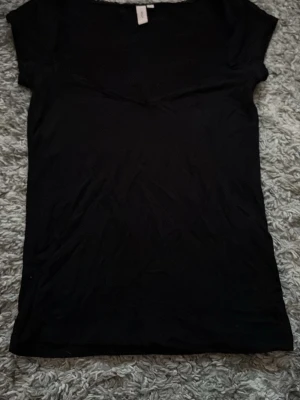 Svart Nelly topp  - En enkel svart topp med v-ringa hals och korta ärmar.