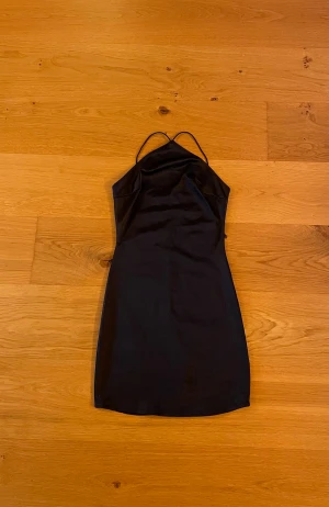 Svart kort klänning från NLY ONE - Säljer en svart, stilren kort klänning från NLY ONE i storlek S. Klänningen har tunna axelband och en figurnära passform med slät yta. Perfekt till fest!