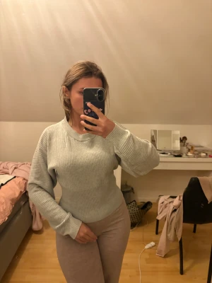 Ljusgrå ribbad stickad tröja - Säljer en ljusgrå stickad tröja med ribbad struktur och rund hals. Tröjan har långärmade, lite bredare ärmar och sitter snyggt med en normal passform. Perfekt för kyliga dagar och enkel att matcha med jeans eller mjukisbyxor. Köpt i usa aldrig använd. 