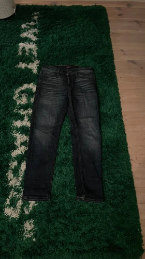 Jeans från Jack & Jones - Modell: Tapered Mike, skick:8/10 (litet slitage ovanför höger bakficka (se bild 3). Annars ett par sköna jeans som sitter bra och använts runt 3 månader