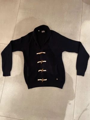 Cardigan tröja - Tja! Säljer en riktigt snygg cardigan från märket Adolfo Domingues, mörkblå färg och snygga detaljer framtil med trä som ni ser på bilderna! Skicket är 10/10 och inga defekter alls och storleken är S och passar bra på killen på bilden som är 185cm lång! Tveka inte på att höra av dig vid minsta lilla fundering eller fråga!!!🤗mvh EM_resell