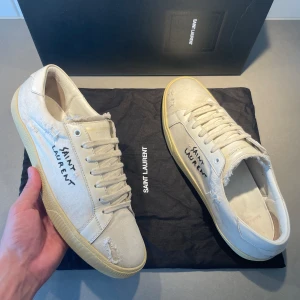 Saint Laurent skor  - Äkta Saint Laurent (SL06) sneakers | Skick: 7,5/10 slitningarna är en del av designen| Storlek 46 fits 47 | Skopåse & kort från Farfetch ingår, kan möjligen fixa box om det är viktigt| Fraktar inom 24H efter köp, på köparens bekostnad 📦 | Hör av dig vid minsta fråga eller fundering 💭