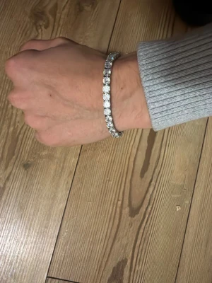 Moissanite tennisarmband från GRA - Snyggt tennisarmband från GRA med gnistrande moissanite-stenar, 5 mm i diameter och 0.3 ct per sten. Armbandet har en klassisk, stilren design i 925 s metall som verkligen poppar på handleden. Perfekt för dig som gillar bling och vill sticka ut.