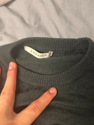 Mörkgrön stickad tröja från A Day's March - Säljer en stilren mörkgrön stickad tröja från A Day's March i storlek M. Tröjan har rund hals, långa ärmar och ribbade muddar vid hals, ärmslut och nederkant. Perfekt för lager-på-lager och chill dagar.