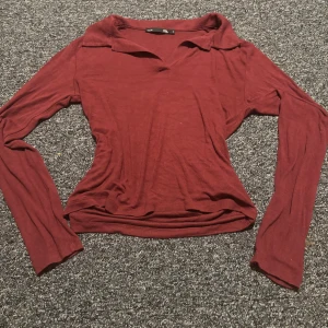 Vinröd långärmad topp från 157 - Säljer en vinröd långärmad topp från 157 med krage och v-ringad hals. Toppen har en slim passform och är tillverkad i mjuk bomull. Perfekt för dig som gillar stilrena och enkla plagg med lite edge. Tröja har ett litet litet håll i höger arm inte alls synligt 