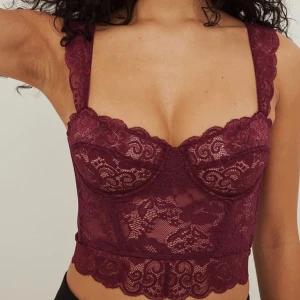 Vinröd spetskorsett med breda axelband - Säljer en vinröd korsett med breda spetsprydda axelband och vacker blommig spets över hela toppen. Modellen är croppad med markerade kupor och dekorativ kant nedtill. Perfekt för dig som vill ha en statement piece med romantisk vibe. Använd enstaka tillfällen. Har klippt bort lappen då den syntes igenom.💕