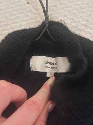 Svart polotröja från Gina Tricot XS - Säljer en svart polotröja från Gina Tricot i ullblandning. Tröjan har korta ärmar och en hög krage som ger en clean och stilren look. Perfekt att matcha med jeans eller kjol för en enkel men snygg outfit. Endast använd 1 gång så den är som ny.