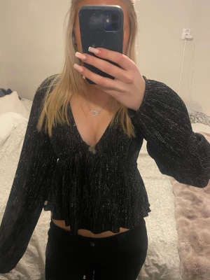Svart glittrig topp - Säljer en svart glittrig topp från Gina Tricot med v-ringning. Tröjan är endast använd 1 gång🩷