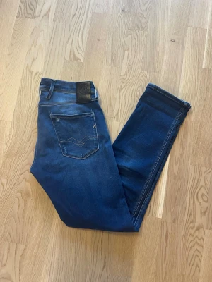 Blå Replay Anbass jeans W30 L32 - Jag säljer dom här riktigt snygga Replay Anbass jeansen i storlek W30 L32. De är i fint skick med snygga slitningar vid fickorna. Tveka inte att höra av er!                                                                            Mått: Längd=101cm. Midja=40cm