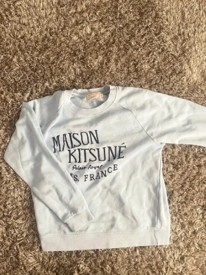 Maison Kitsuné ljusblå sweatshirt🙌🤩 - Snygg ljusblå sweatshirt från Maison Kitsuné med svart texttryck på bröstet där det står 'Maison Kitsuné'. Tröjan har rund halsringning och långa ärmar. Perfekt för en avslappnad och trendig look.🙌🤩