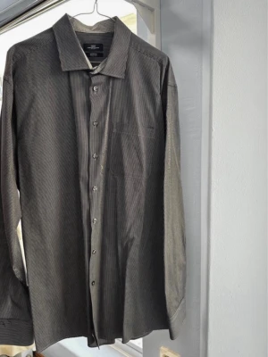 Randig skjorta Lorenzo Calvino XXL - Snygg svart och vit randig skjorta från Lorenzo Calvino i storlek XXL. Skjortan har klassisk krage, bröstficka och knappar framtill. Tillverkad i ett lättskött material som känns bekvämt och stilrent.