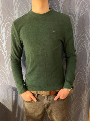 Mörkgrön tröja Tommy Hilfiger - Snygg mörkgrön långärmad tröja från Tommy Hilfiger med diskret logga på bröstet. Tröjan har en enkel, clean design och är gjord i mjuk bomull. Perfekt till jeans för en chill look. Modellen är 182 cm