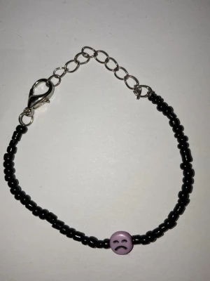 Svart pärlarmband med lila detalj - Hangjort armband av mig som är stilrent med små svarta pärlor och en större lila pärla i mitten. Justerbar längd med silverfärgat kedjelås. Perfekt accessoar för att lyfta din outfit. Frakt 22 till 100 kr beroende på vikt. Kontakta mig om du har frågor eller vill köpa.