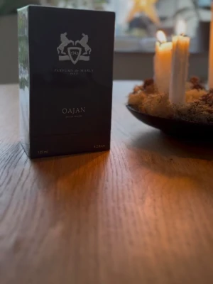 Parfums de Marly Oajan EdP 125ml - Lyxig parfym från Parfums de Marly, Oajan Eau de Parfum, i en elegant mörk kartong med silverdetaljer och logga. Flaskan rymmer 125 ml och doften är känd för sina varma, kryddiga och söta toner. Perfekt för dig som vill sticka ut med en exklusiv signaturdoft. Ungefär 110 ml kvar den är en R#plica 