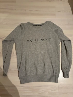 Grå Acqua Limone Classic sweatshirt - Säljer en grå sweatshirt från Acqua Limone. Klassisk modell med tryck både fram och bak. Tröjan är använd lite utan några defekter. Hör av dig vid intresse! 😃