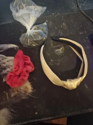 diadem och scrunchie i sammet - Säljer ett brett, glansigt beige diadem med twistad design samt en röd scrunchie i mjuk sammet. Perfekta accessoarer för att lyfta din frisyr med både stil och färg. Båda är bekväma och passar till många olika looks.