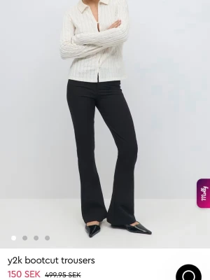 Svarta bootcut byxor Y2K - Snygga svarta bootcut byxor i Y2K-stil med två knappar framtill och fickor bak. Byxorna har en figurnära passform upptill och utsvängda ben. Perfekta till sneakers eller boots för en trendig look. De ser exakt ut som på bilden och är helt slutsålda på hemsidan💗