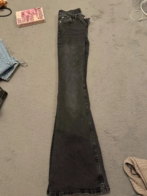 Svarta bootcut jeans från 157 - Säljer ett par svarta bootcut jeans från 157 med klassisk femficksmodell och silverfärgade nitar. Jeansen har en snygg tvättad look och är tillverkade i ett mjukt jeansmaterial. Perfekta för dig som gillar retrovibbar och vill ha ett par riktigt schyssta byxor.