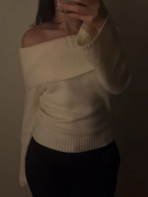 Offshoulder vit stickad tröja - Säljer en superfin offshoulder stickad tröja i vitt. Tröjan har bred ribbad kant upptill och vid midjan, vilket ger en snygg och bekväm passform. Perfekt för dig som vill ha en trendig och mysig look till hösten eller vintern.