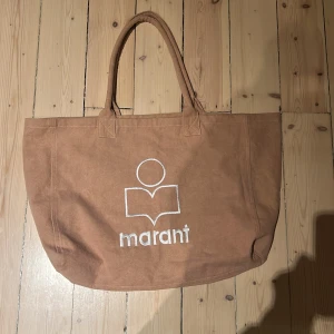 Gammelrosa shoppingväska från Marant - Rymlig gammmelrosa shoppingväska från Marant i bomull med vita broderade detaljer och logga på framsidan. Väskan har två handtag och rymligt huvudfack, perfekt för att bära med sig allt man behöver. 