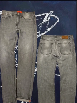 Gråa jeans från Mads Nørgard med orange detalj - Snygga gråa jeans från Mads Nørgard med klassisk femficksmodell och en cool orange detalj vid benslutet. Jeansen har raka ben och en läderpatch med logga bak i midjan. Perfekta för en avslappnad och trendig look. As feta orangea sömmar som sticker ut! Sitter som 31/33