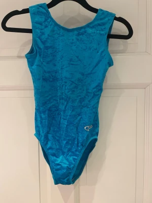 Blå gymnastikdräkt  - Säljer min gamla träningsdräkt inom AG gymnastik. Modellen har breda axelband, rund halsringning och en liten logga framtill. Storlek 146-152