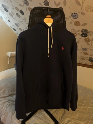 Ralph lauren Hoodie - En klassisk marinblå Polo Ralph lauren hoodie. Storlek L men skulle säga att den passar mer  som en M. Knappt använd och tvättad en gång. Äkta givetvis. Passar riktigt bra till många stiler och perfekt nu till vintern. Nyskick! 