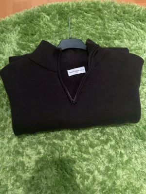 Svart halvzip tröja Three Glory Days - Mörk stickad tröja från Three Glory Days med halvzip och hög krage. Tröjan är mörkbrun, har långa ärmar och är tillverkad i ett mjukt material som passar perfekt för kyligare dagar. Enkel och stilren design som funkar till det mesta. Hör av er vid funderingar🙌