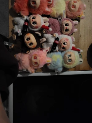 Samlingspaket med söta nalle-dockor - Säljer ett paket med åtta labubus i olika pastellfärger, alla utklädda till djur och med stora ögon. Några håller små Coca-Cola-flaskor och har tomteluvor. Perfekt för dig som gillar samlarprylar eller vill ge bort något unikt! Även en sekreterare labubu.