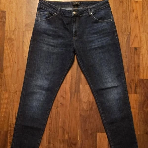 Philipp Plein x Playboy Slim Jeans - W33 L31 - Mörkblå jeans från Philipp Plein x Playboy med slim cut, snygga kontrastsömmar och metallknapp med PP-logga. Baktill finns en patch med Playboy Plein och en hexagonformad PP-dekal på fickan. Klassisk femficksmodell i jeansmaterial.