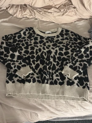Leopardmönstrad stickad tröja från VILA - Säljer en beige och svart stickad tröja från VILA med leopardmönster. Tröjan har rund halsringning, ribbade muddar och nederkant samt lång ärm. Perfekt för dig som vill ha en trendig och mysig look. Storleken är xl men passformen är M.