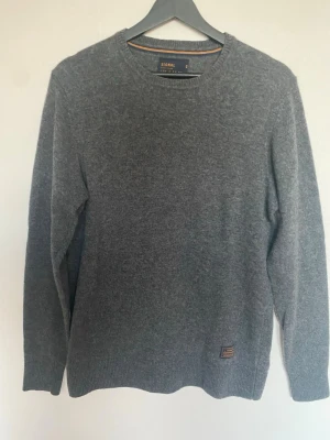 Mörkgrå ulltröja från Signal - Mysig grå stickad tröja från Signal, tillverkad av italienskt garn. Rund halsringning och ribbade muddar vid ärmslut och nederkant. Perfekt för kyliga dagar och enkel att matcha med jeans eller chinos.
