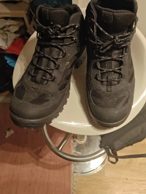 Svarta kängor från Ecco - Säljer ett par svarta kängor från Ecco med robust sula och snörning. Kängorna har en sportig design med detaljer i syntet och textil, samt metallhål för snören. Perfekta för dig som gillar outdoor och vill ha bekväma skor. Ps knappt använda?? Ps har inte Swish kom gärna till mig