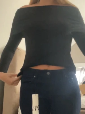 Svart offshoulder topp - Trendig svart offshoulder topp med lång ärm. Tillverkad i mjukt material som sitter snyggt mot kroppen. Storlek M, knappt använd. 