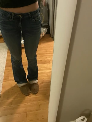 Blå bootcut jeans med låg midja - Säljer ett par blå bootcut jeans med låg midja och klassisk femficksdesign. Jeansen har en snygg tvättad look och är tillverkade i mjukt denimtyg som sitter skönt. Klippt av lappen men de är ifrån Zara och i storlek S, knappt använda nytt skick 